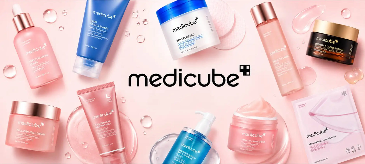 Produits de skincare medicube rose et bleu disposés sur un fond rose tendre avec des gouttelettes d’eau.